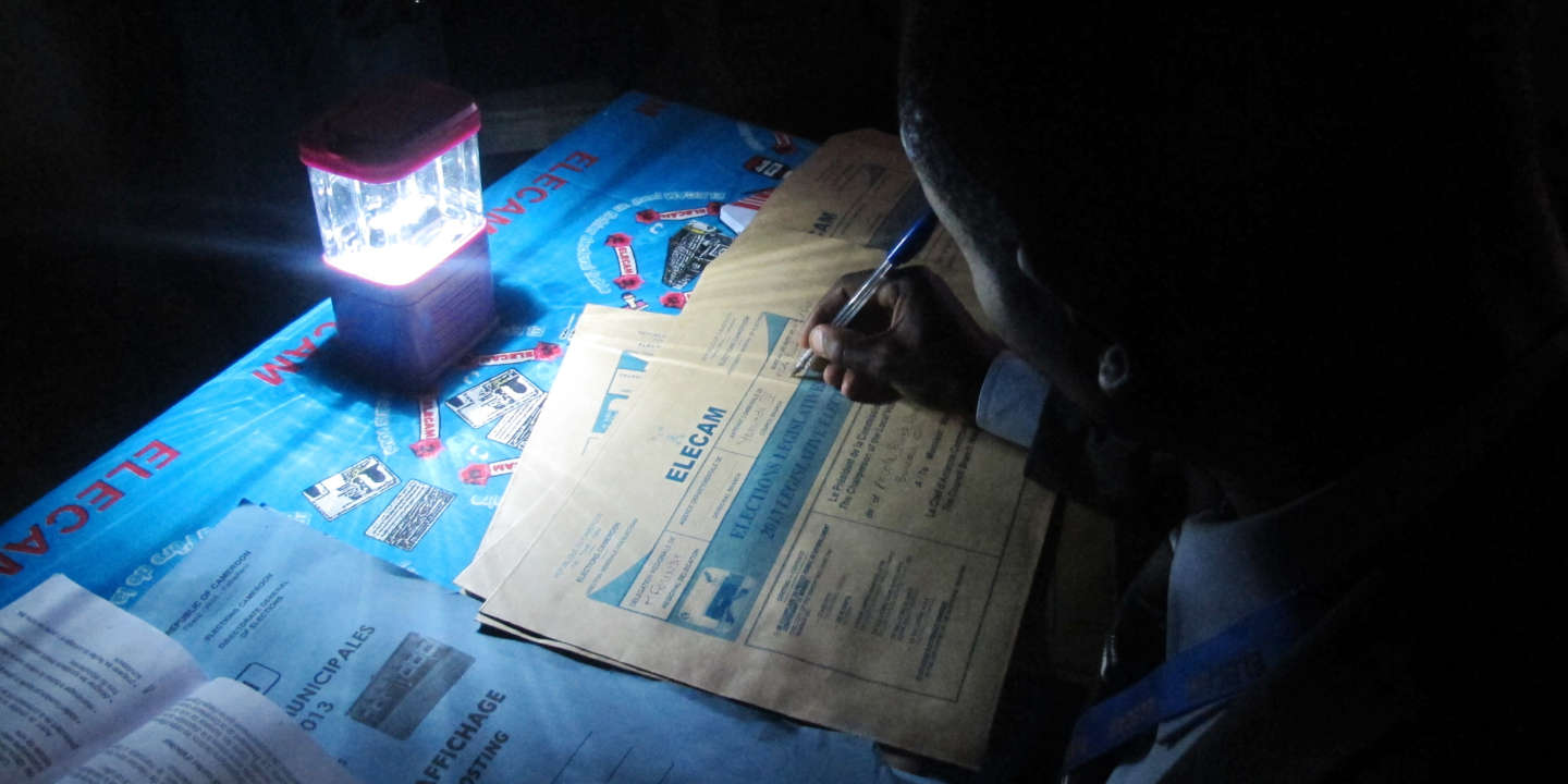 Un président de bureau de vote rempli les procès verbaux avec une lampe